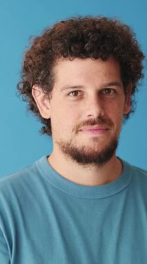 Yaklaş, mutlu adam iyi bir jest yapıyor. Stüdyonun mavi arka planında izole edilmiş.