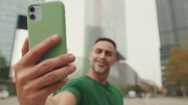 Cep telefonuyla selfie çeken orta yaşlı bir adamın yakın çekimi.