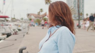 Güzel gülümseyen orta yaşlı kadın limanda oturuyor ve deniz manzarasına bakıyor.