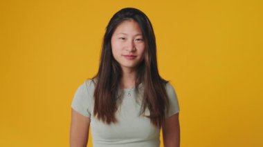 Stüdyoda sarı arka planda baş parmak gösteren genç bir kadın görülüyor.