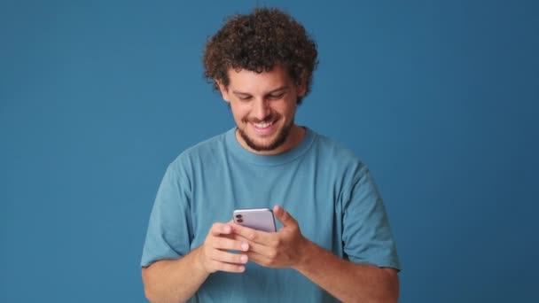 Γέλιο Άνθρωπος Κρατώντας Τηλέφωνο Στο Στούντιο Μπλε Φόντο — Αρχείο Βίντεο
