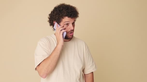 Мужчина Эмоционально Говорит Мобильному Телефону Студии Бежевом Фоне — стоковое видео