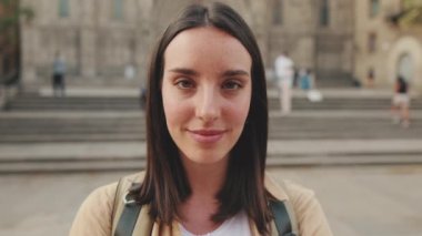 Yakın çekim, gülümseyen kadın eski binanın arka planında kameraya bakıyor.