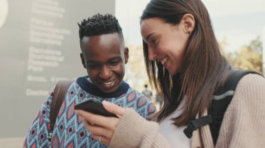 Close-up of a guy and a girl talking to each other and using a mobile phone