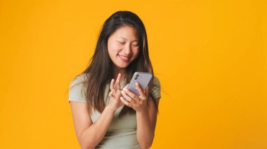 Akıllı telefon ekranında gülümseyen kız sosyal ağlara göz atıyor, beyaz arka planda izole edilmiş mesajlar yazıyor.