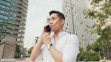 Genç işadamı, modern binalarda akıllı telefondan konuşuyor.