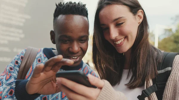 Close-up of a guy and a girl talking to each other and using a mobile phone