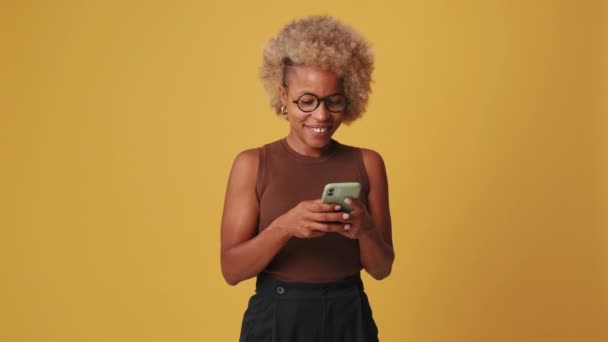 Usmívající Žena Pomocí Mobilního Telefonu Ukazující Palce Nahoru Izolované Oranžovém — Stock video