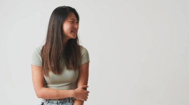 Gülümseyen ve gülümseyen genç bir kadın, beyaz arka planda izole edilmiş, stüdyo çekimi.