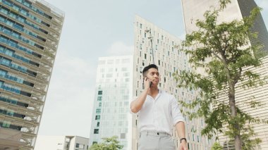 Genç işadamı, modern binalarda akıllı telefondan konuşuyor.