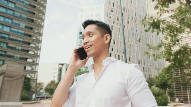 Genç işadamı, modern binalarda akıllı telefondan konuşuyor.