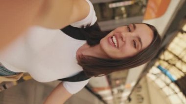 Kadın gezgin tren istasyonundaki cep telefonundan görüntülü arama yapıyor.