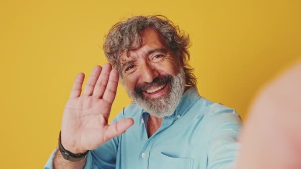 Šťastný Starší Muž Vypadá Kamera Dělat Videohovor Pozdrav Izolované Oranžovém — Stock video
