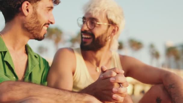 浪漫的时刻 一对同性恋夫妇在黎明时分坐在海滩上 交叉着双臂 彼此深情地望着对方 — 图库视频影像