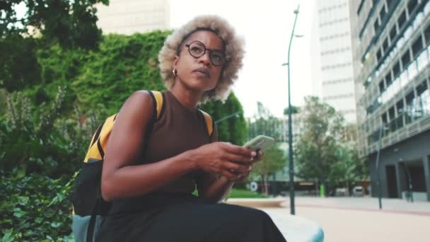 Γυναίκα Σακίδιο Στους Ώμους Χρησιμοποιώντας Κινητό Τηλέφωνο Σύγχρονα Κτίρια Φόντο — Αρχείο Βίντεο