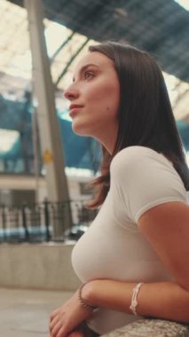 Genç bayan gezgin tren istasyonunda oturmuş treni bekliyor.