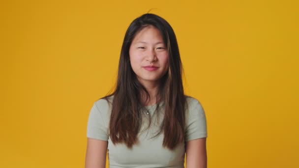 Genç Bir Kadın Çırpıyor Kameraya Bakıyor Stüdyoda Sarı Arka Planda — Stok video
