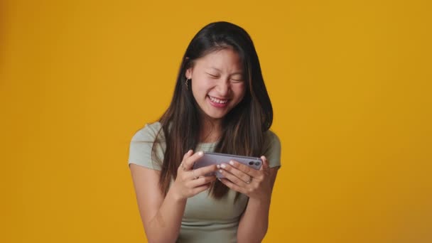 Leende Ung Kvinna Tittar Rolig Video Mobiltelefon Isolerad Över Gul — Stockvideo