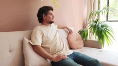 Oturma odasındaki kanepede dinlenen adam.