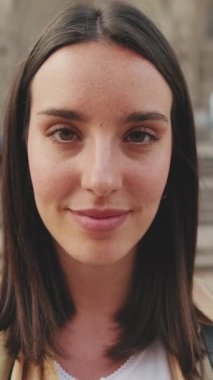 Yakın çekim, gülümseyen kadın eski binanın arka planında kameraya bakıyor.