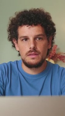 Oturma odasında oturan adam dizüstü bilgisayara bakıyor.