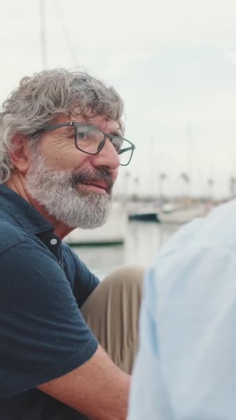 快乐的老人坐在码头上 专心致志地听着别人说话 — 图库视频影像
