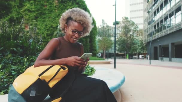 Usmívající Žena Batohem Pomocí Mobilního Telefonu Zatímco Sedí Venku — Stock video