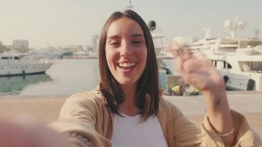 Kapatın, gezgin kadın marinadayken cep telefonuyla video görüşmesi yapıyor.