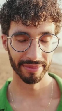 Genç adamın gözlerini açtığı ve kameraya gülümseyerek baktığı yakın plan.