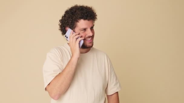 Happy Άνθρωπος Μιλάει Συναισθηματικά Στο Κινητό Τηλέφωνο Στο Στούντιο Μπεζ — Αρχείο Βίντεο