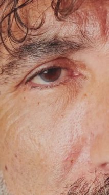 Yakın plan, yaşlı, gri saçlı bir adamın gözü gözlerini açıyor ve kameraya bakıyor.