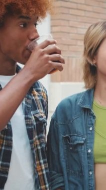 Şirket arkadaşları ellerinde içkilerle şehir caddesinde yürüyor, sohbet ediyor ve gülüyorlar.