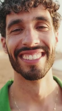 Genç adamın gülümseyerek kameraya baktığı yakın plan.