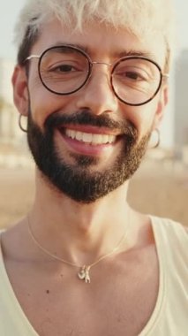 Genç adamın gülümseyerek kameraya baktığı yakın plan.