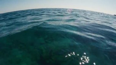 Ufuk çizgisi kıvrımlı suyun yüzeyinde. Kamera suyun üzerinde aşağı doğru hareket ediyor. Deniz yüzeyindeki küçük dalgalar, alçak açılı çekim, deniz manzarası