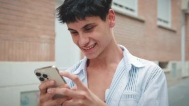 Dışarıda cep telefonu kullanan gülümseyen genç adam.