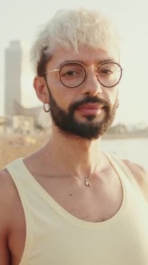 Gülümseyen genç adam kameraya bakıyor ve kollarını kavuşturuyor.