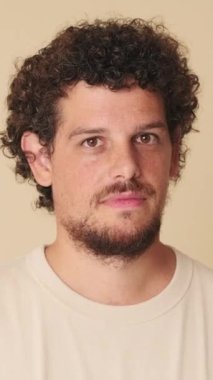 Kameraya bakan adamın yakın çekimi. Bej arka planda stüdyoda göz kırp.