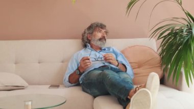 Yaşlı bir adam rahat oturma odasındaki kanepede dinleniyor.