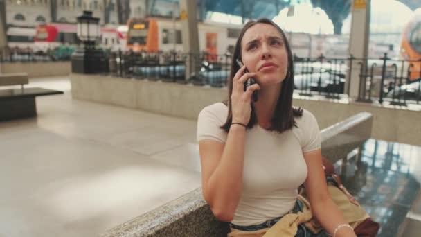 Reisende Kvinne Som Sitter Jernbanestasjonen Snakker Smarttelefon – stockvideo