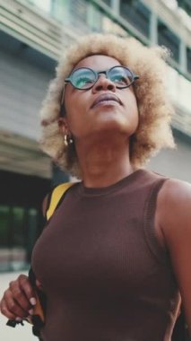 Sırt çantalı genç bir kadın modern binalarda sokakta yürüyor.