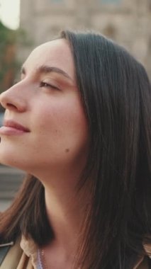 Yaklaş, kadın kafasını çevirir ve eski bir binanın arka planında gülümseyerek kameraya bakar.