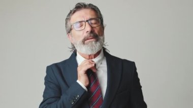 Orta yaşlı işadamı sinirli, tasmasını çekmiş, gri arka planda izole edilmiş.