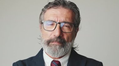 Gri arka planda izole edilmiş kameraya bakan gözlüklü iş adamlarının yakın çekimi.