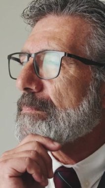 Yaklaş, işadamı eli destekli çene başını çevirir ve gri arka planda kameraya bakar.