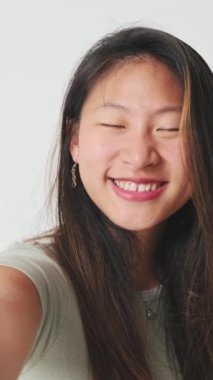 Stüdyoda özçekim yapan genç bir kadın beyaz arka planda izole edilmiş.