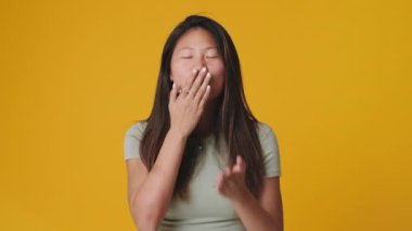 Stüdyoda sarı arka planda hava öpücüğü yollayan genç bir kadın.