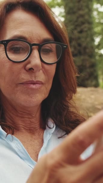 Närbild Vackra Äldre Kvinna Glasögon Med Hjälp Telefon När Sitter — Stockvideo