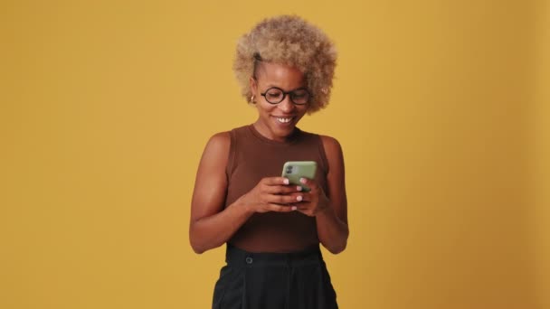 オレンジ色の背景の携帯電話で笑顔の女性チャット — ストック動画