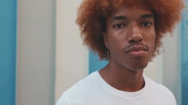 Yaklaş, genç adam çizgili duvardaki kameraya bakıyor.